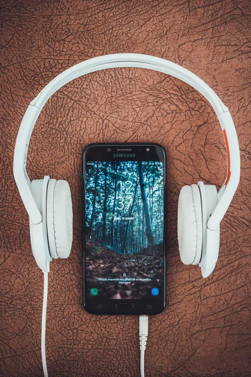 turned on black samsung smartphone between headphones